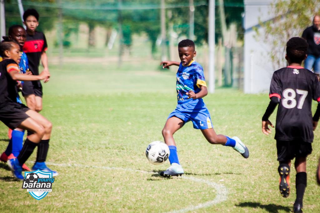 A player of the Young Bafana Soccer Academy about to shoot a football on a soccer pitch in South Africa.