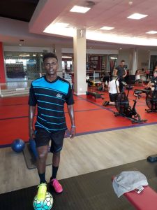 Eyona Ndondo, former player of the Young Bafana Soccer Academy, standing on a football at a gym.
