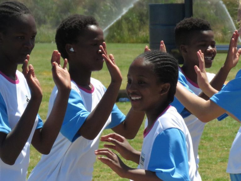 Smiling Participants of the Young Bafana Girls Camp by Julia Simic doing an exercise with clapping.