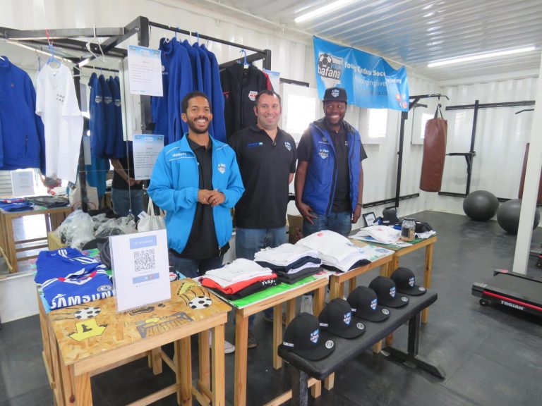 Three members of the Young Bafana Soccer Academy staff selling merchandise during the YB Arena opening.
