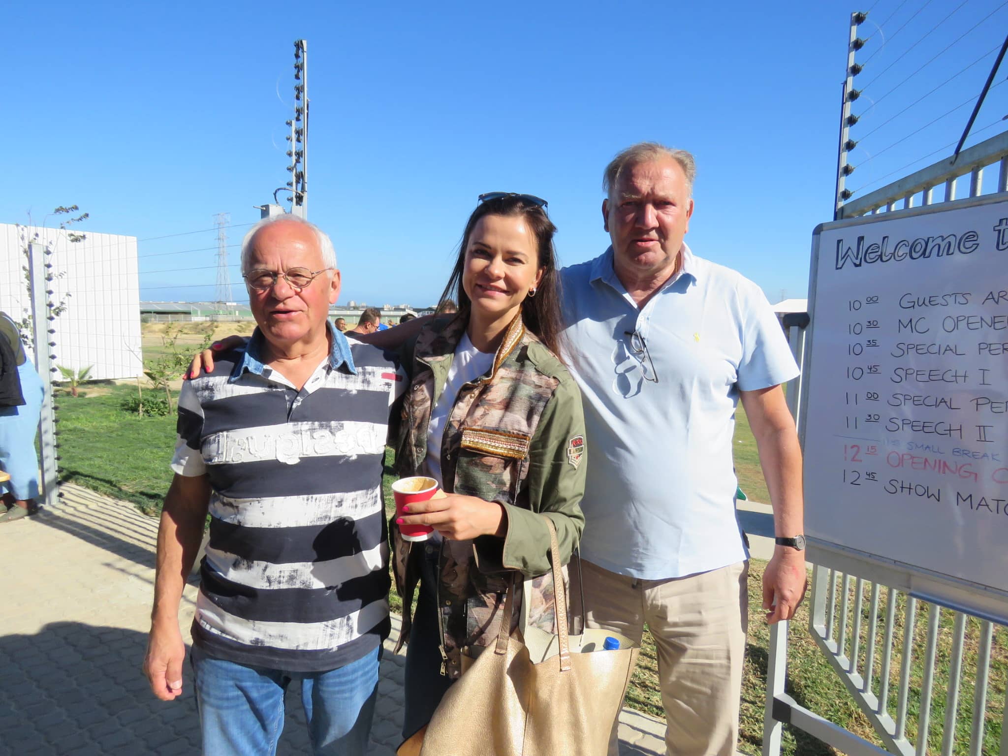 Three visitors of the Young Bafana Arena opening in South Africa standing next to the event timetable.