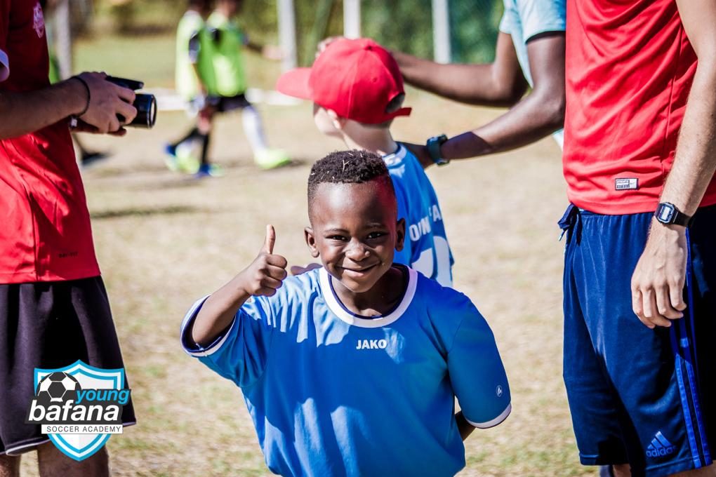 A player of the NGO Young Bafana Soccer Academy smiling to the camera and giving a thumbs up.